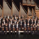 Großes Orchester posiert vor Orgel auf Bühne