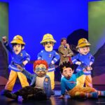 Feuerwehrmänner und Kinderfiguren auf einer Theaterbühne